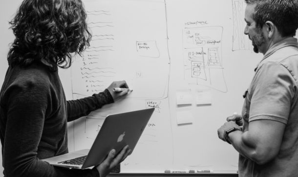 Dos profesionales diseñando un proceso comercial en una pizarra